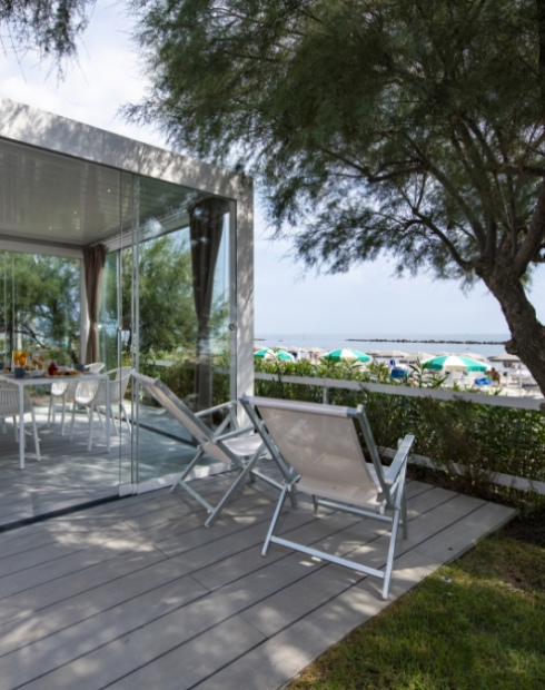 Terrazza moderna con sedie, vista mare e spiaggia, atmosfera rilassante e vacanziera.